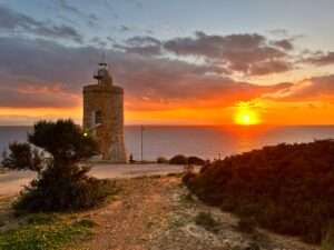 sun setting into the ocean, a lighthouse