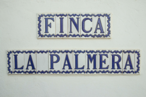 letters written on ornamentic tiles spelling out Finca la Palmera glued to a white wall