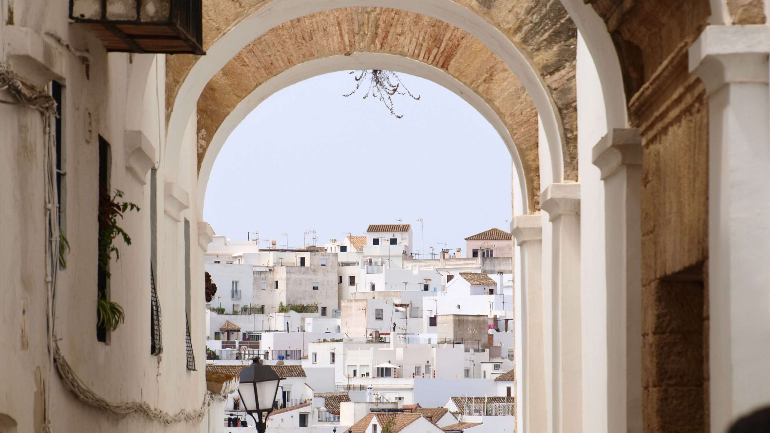 an arch of an old building, through it white houses